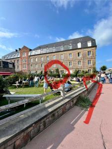 Un edificio con una cinta roja delante de un edificio. en Belle vue sur la mer, en Veules-les-Roses