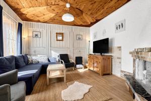a living room with a blue couch and a tv at Chalupa pod stromy in Kovářská