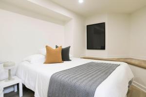 um quarto branco com uma cama e uma televisão na parede em The Ember Suite em Peterborough