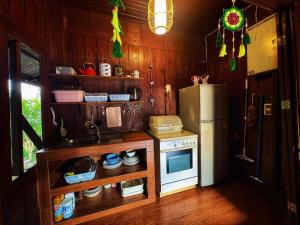 a small kitchen with a refrigerator and a stove at Thai Classic House Rimtalay in Ban Rong Po