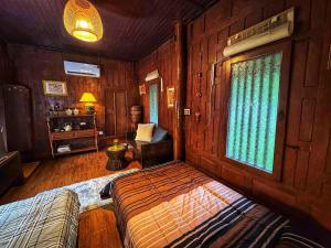 a bedroom with wooden walls and a bed and a window at Thai Classic House Rimtalay in Ban Rong Po