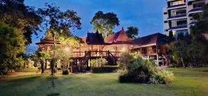 a large house with a yard in front of a building at Thai Classic House Rimtalay in Ban Rong Po