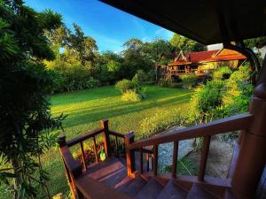 a wooden staircase leading to a house with a yard at Thai Classic House Rimtalay in Ban Rong Po +14 photos