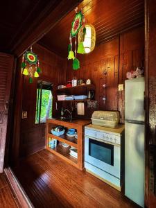 a kitchen with a stove and a refrigerator at Thai Classic House Rimtalay in Ban Rong Po