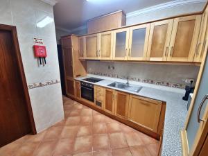 Una pequeña cocina con gabinetes de madera y un fregadero. en Brisa Tejo, en Alcochete