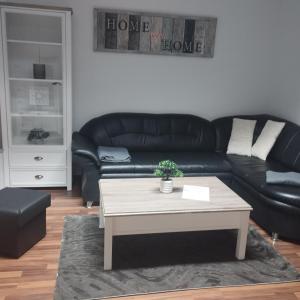 a living room with a black leather couch and a coffee table at Fewo Am Waldrand in Heideblick