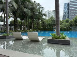 zwei weiße Stühle mitten im Pool in der Unterkunft Lang Retreat Apartment - Resort Pool & Elite Gym in Ho-Chi-Minh-Stadt