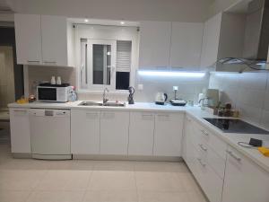 a white kitchen with a sink and a microwave at Theo Luxury House in Patra