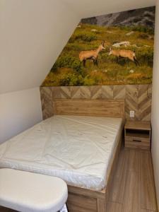 1 cama en una habitación con un cuadro en la pared en Rusiński Raj - Domki, en Bukowina Tatrzańska