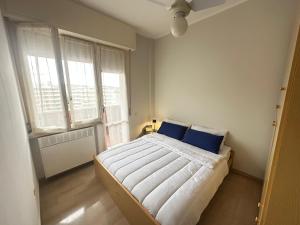 a bedroom with a bed with blue pillows and two windows at Tra Cielo e Mare da Vale in Fano