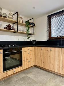 a kitchen with wooden cabinets and a black appliance at Domek Sosna 