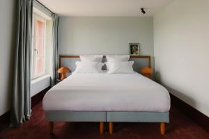 a bedroom with a large white bed with a window at Repère Sauvage in La Ville-aux-Clercs