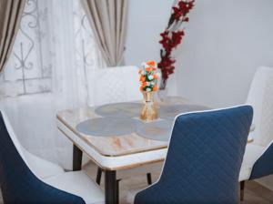 ein Tisch mit einem blauen Stuhl und ein Tisch mit einer Blumenvase in der Unterkunft Royaltron apartment services in Ibadan