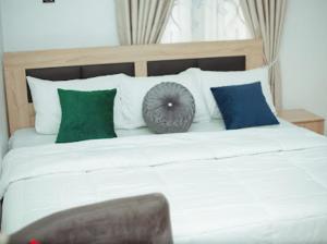 ein großes weißes Bett mit grünen und blauen Kissen in der Unterkunft Royaltron apartment services in Ibadan