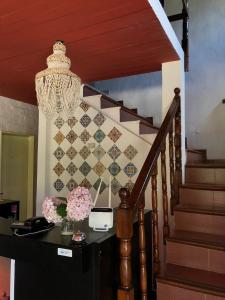 a staircase with a chandelier and a table with flowers at Hostería Michel in Villa Gesell