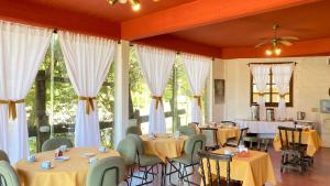 a dining room with tables and chairs and windows at Hostería Michel in Villa Gesell