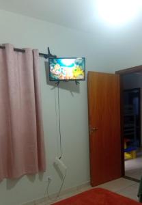 a flat screen tv on a wall next to a door at bairro Oliveira - casa 3 quartos com ar in Campo Grande +24 photos