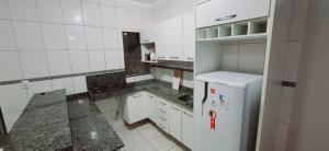 a white kitchen with a refrigerator and a counter at bairro Oliveira - casa 3 quartos com ar in Campo Grande