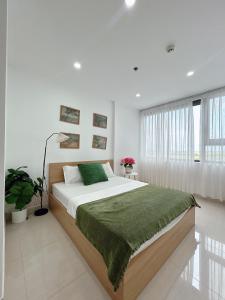 a bedroom with a large bed with a green blanket at Minh Anh Apartment 2 in Thôn Văn Dương +20 photos