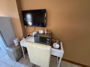 ウェルコムにある3 Schnehage Guesthouseのデスク、電子レンジ、テレビが備わる客室です。