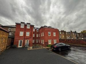 HanwellにあるLuxury 1BR Modern Flat in London W7 with Private Parkingの赤レンガの建物の前に駐車された黒い車