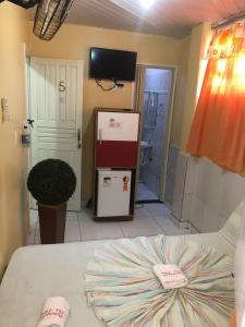 a room with a bed and a refrigerator at Pousada Tia Tita in Cayru