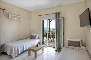 1 Schlafzimmer mit 2 Betten, einem TV und einem Balkon in der Unterkunft Kefalonian Oneira Villas in Mousata