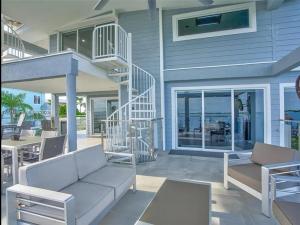 a house with a porch with a couch and a staircase at Oceanfront Mansion With Boat & Jet Ski in Key Largo