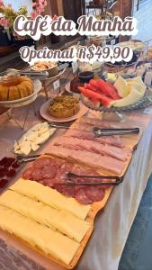 een tafel met kaas, vlees en andere voedingsmiddelen bij Pousada Villa Bergamin, Monte Verde in Monte Verde