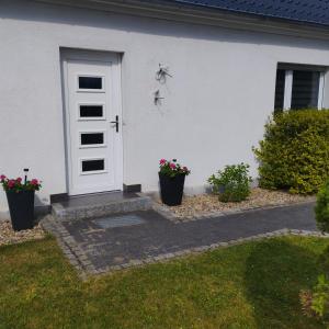 a white house with a white door and some flowers at Fewo Am Waldrand in Heideblick