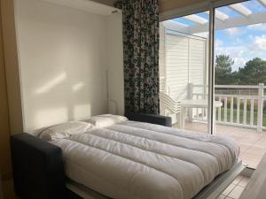 een groot bed in een slaapkamer met een balkon bij Les Sables-d'Olonne - Vue Mer, Terrasse, Wifi Fibre & Piscine, à 2 pas de l'Océan - E101 in Les Sables-dʼOlonne +33 foto's