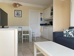 een woonkamer met een blauwe bank en een keuken bij Les Sables-d'Olonne - Vue Mer, Terrasse, Wifi Fibre & Piscine, à 2 pas de l'Océan - E101 in Les Sables-dʼOlonne
