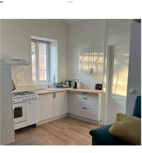a kitchen with white cabinets and a stove top oven at Appartement calme in Sigogne