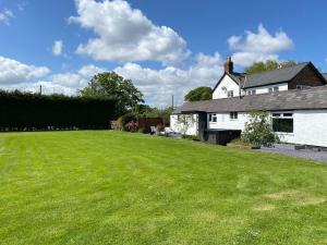Una casa blanca con un gran jardín delante de ella. en Peewit Lodge, 