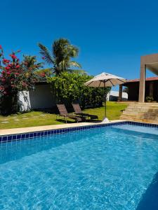 トライリにあるCasa Paraíso Guajiruの大きなスイミングプール(パラソル、椅子2脚、パラソル付)