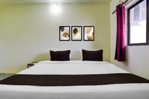 a bedroom with a white bed with three pictures on the wall at HOTEL O REEYH INN in Khāpri +21 photos