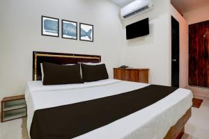 a bedroom with a large bed and a tv at Hotel O Elegance Inn in Virār