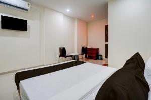 a bedroom with a white bed and a tv at Hotel O Elegance Inn in Virār