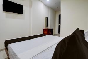 a bedroom with a white bed and a tv on the wall at Hotel O Elegance Inn in Virār