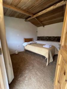 a bedroom with a bed in a room with wooden ceilings at Mamá Raywa in Huari