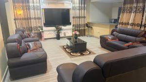 a living room with couches and a flat screen tv at LOUNEL BnB in Kumasi