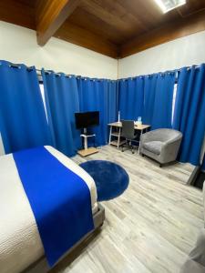 a bedroom with blue curtains and a bed and a desk at Motel Magistral in St-Raphael-de-Bellechasse