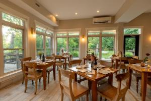 Un restaurante con mesas y sillas de madera y ventanas. en Lóyly Spa Guesthouse, en Ottawa
