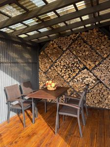 Ein Tisch und Stühle vor einer Wand aus Brennholz in der Unterkunft Domivka котедж із чаном-джакузі, каміном і кіно-зоною у Cлавську in Slawske