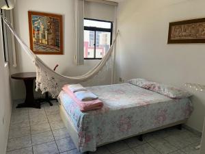 a bedroom with a hammock bed and a table at Apartamento amplo e confortavel in Cabedelo
