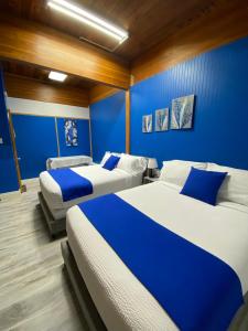 two beds in a room with blue walls at Motel Magistral in St-Raphael-de-Bellechasse
