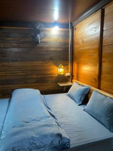 a bedroom with a bed with a wooden wall and a fan at Ha Giang Lake View House in Ha Giang
