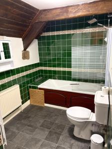 een groene betegelde badkamer met een bad en een toilet bij Three Wheat Heads in Thropton