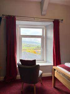 een slaapkamer met een raam met een stoel ervoor bij Three Wheat Heads in Thropton +21 foto's