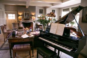 a living room with a piano and a fireplace at Romantik B&B Zonnehuis in De Haan